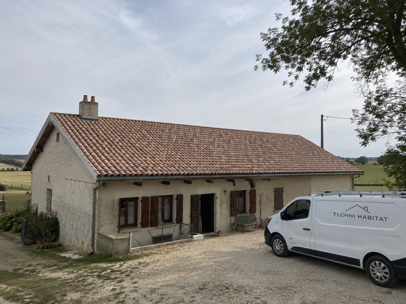 Maison avec toiture rénovée par Techni Habitat et véhicule de l'entreprise devant la façade